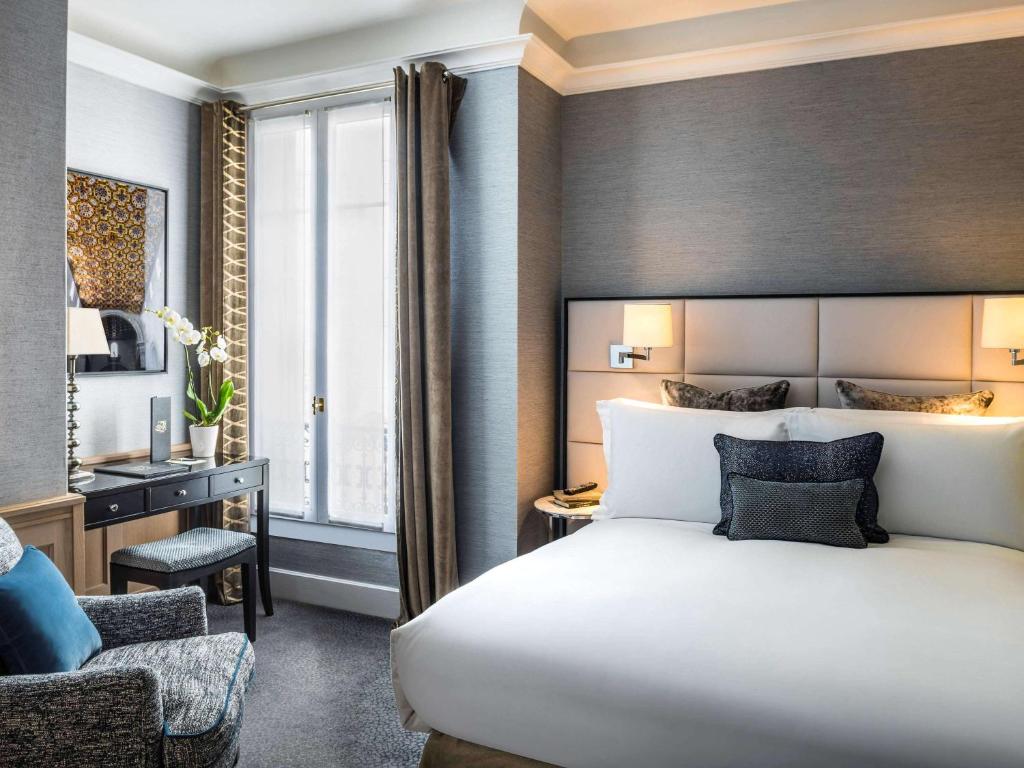 A stylish and comfortable hotel room at Sofitel Paris Baltimore Tour Eiffel, featuring a plush king-sized bed, tasteful furnishings, and a magnificent view of Paris from the window