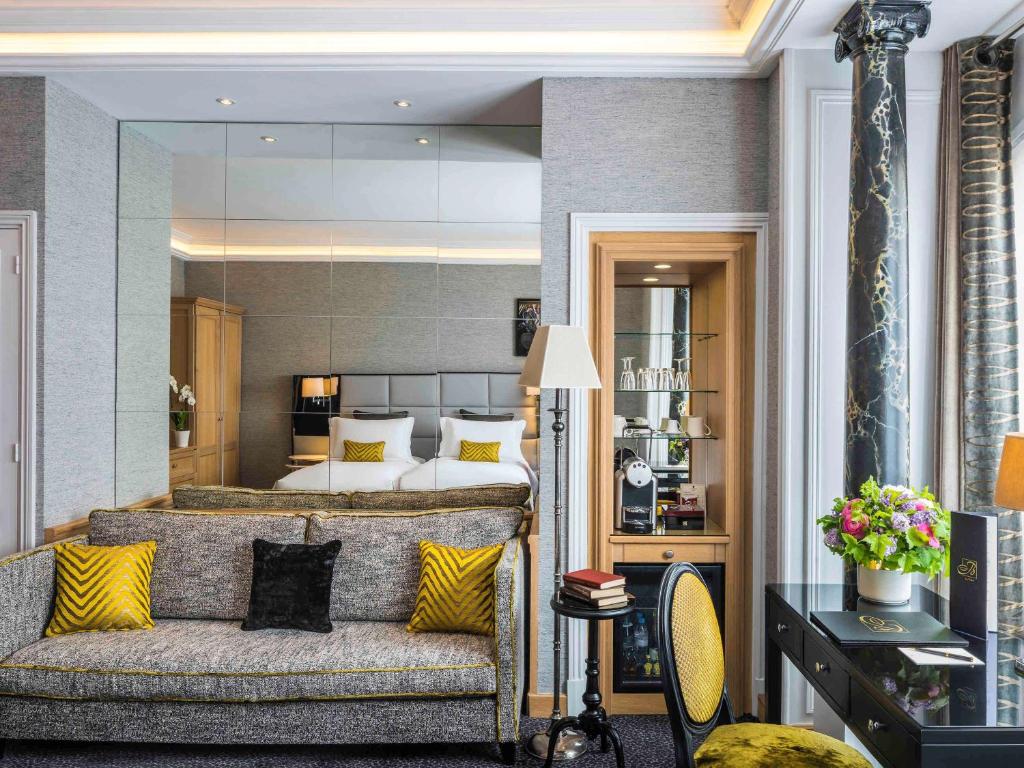 Luxurious hotel room at Sofitel Paris Baltimore Tour Eiffel, with a comfortable king-sized bed, chic decor, and a stunning view of the Eiffel Tower through the large windows