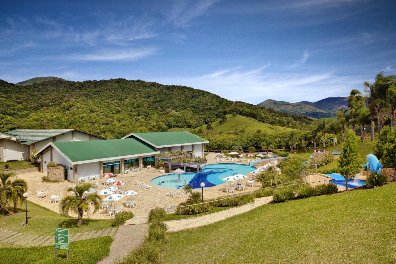Vista aera de piscina e salao com area verde ao redor montanhas no fundo
