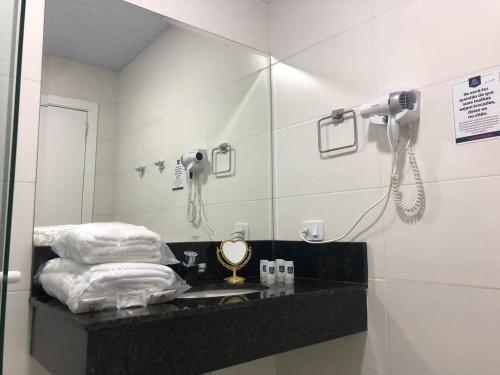 a bathroom with a sink, mirror, and shower stall at Hotel Brasilia Curitiba in Curitiba