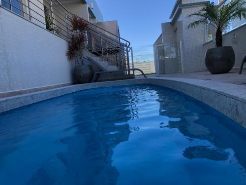 a blue swimming pool in front of a building at Apartamento ingleses in Florianópolis