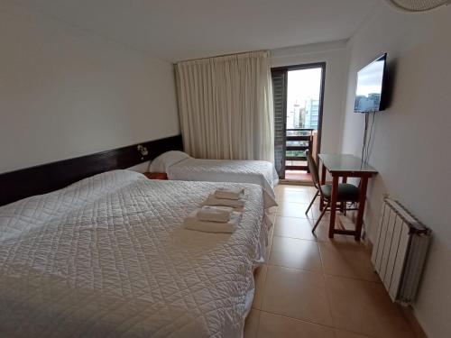 un dormitorio con dos camas y un escritorio y un televisor en Intersur Villa Gesell en Villa Gesell