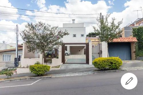 a white house with a gate on a street at Home Office Curitiba/vaga de estacionamento grátis in Curitiba