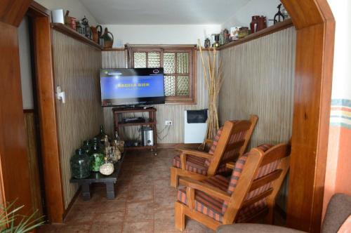 un salón con dos sillas y un televisor de pantalla plana en la Hostería El Bosque de Villa Gesell