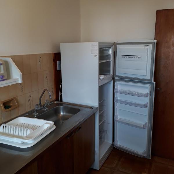 una cocina con nevera abierta junto a un fregadero en Departamentos Bezbel - Mariska en Villa Gesell