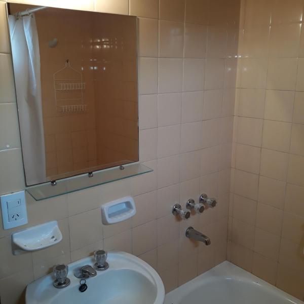 un baño con aseo y ducha con espejo en Departamentos Bezbel - Mariska en Villa Gesell