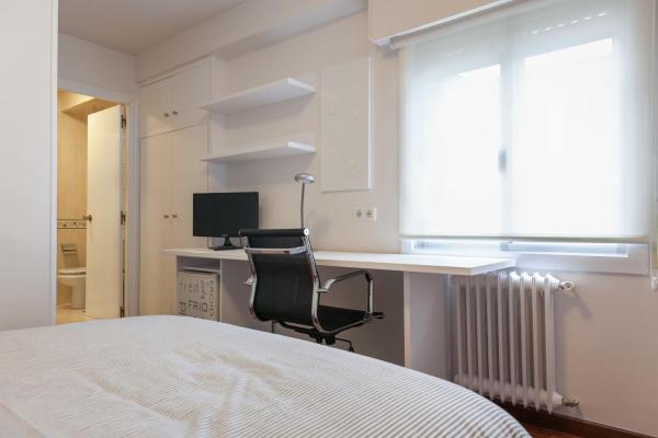 un dormitorio con cama y un escritorio con ordenador en la Pension Residencia F&F de Santiago de Compostela