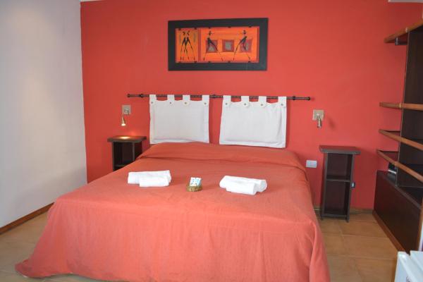 un dormitorio rojo con una cama con dos toallas en Alamos en Villa Gesell