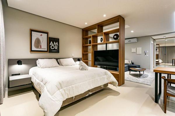 a bedroom with a large bed and a living room at Apartamento moderno em condomínio com infraestrutura de clube CA14I in Florianópolis